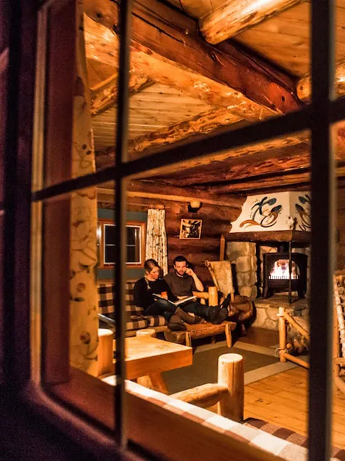 Couple reading by fireplace in lodge