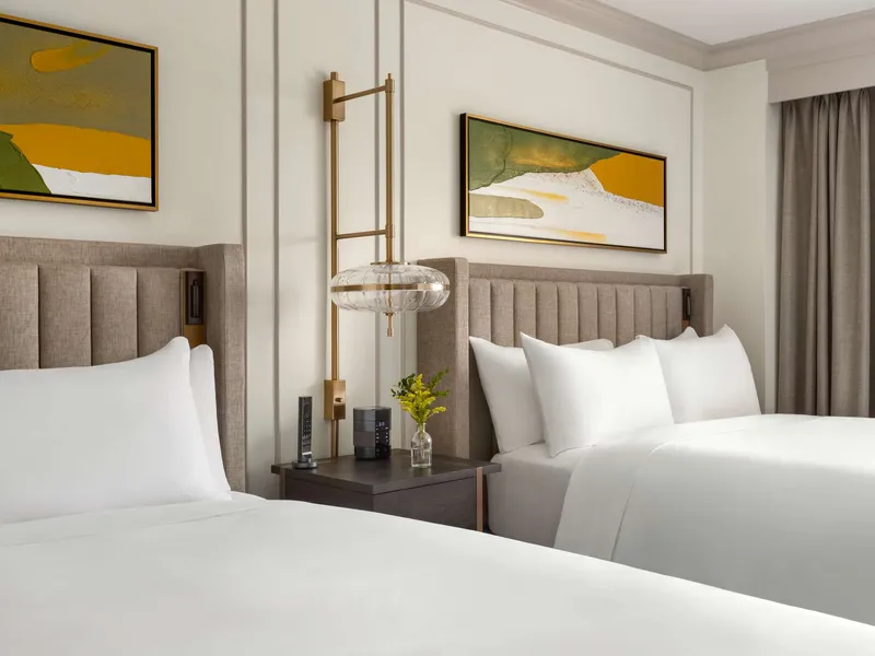 Twin beds with beige upholstered headboards in a Fairmont Lake Louise guest room with modern furnishings.