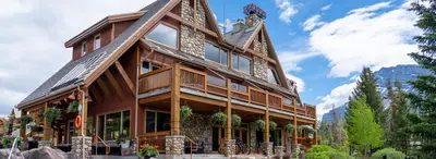 Hidden Ridge Resort timber and stone lodge with wraparound deck overlooking mountain peaks.