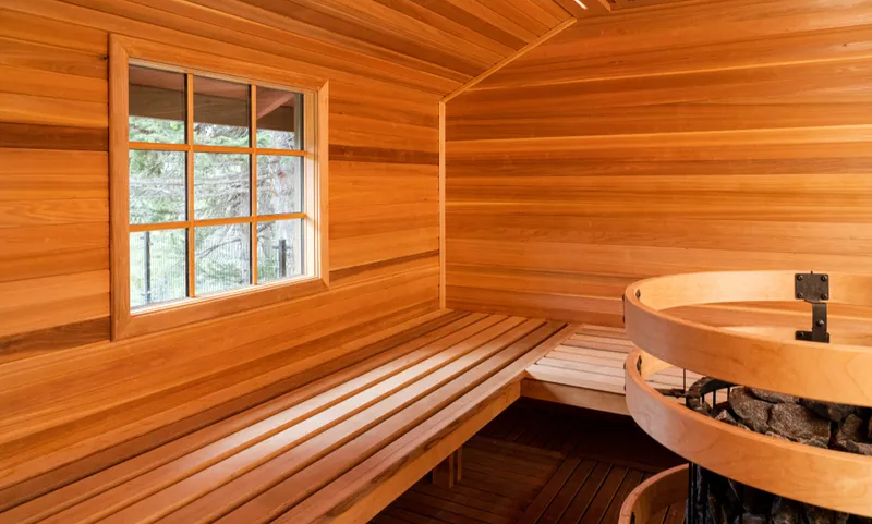 Hidden Ridge sauna with wooden benches, window overlooking forest, and cedar interior.