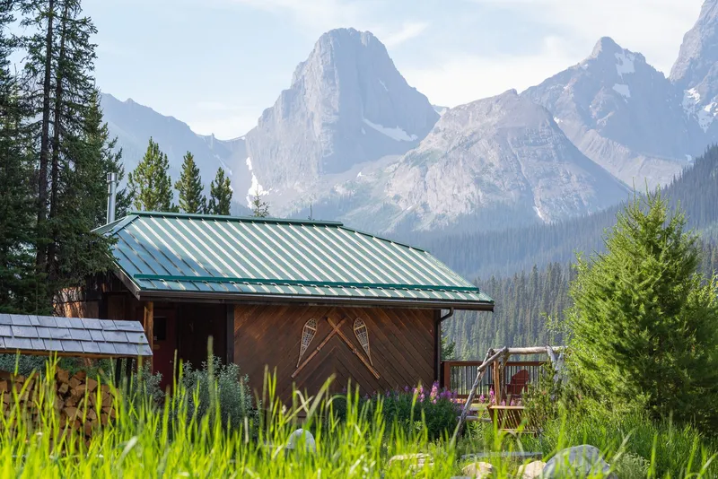 Mount Engadine Lodge's log cabin with metal roof set against dramatic rocky peaks in Kananaskis.