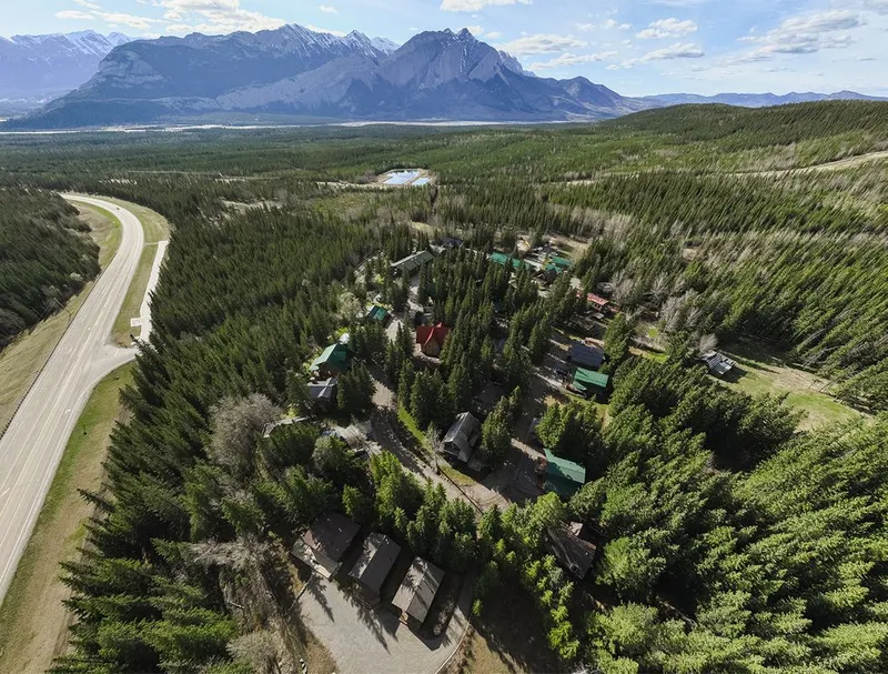 Overlander Lodge nestled among dense coniferous forest with mountain peaks beyond.