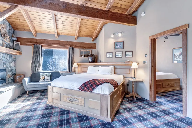 Paintbox Lodge artist loft suite with timber beams, wood bed frame, and stone fireplace.