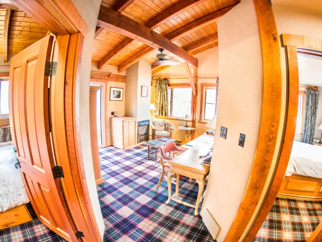 Paintbox Lodge cabin interior with exposed timber beams, wooden doors, and tartan plaid flooring throughout the room.