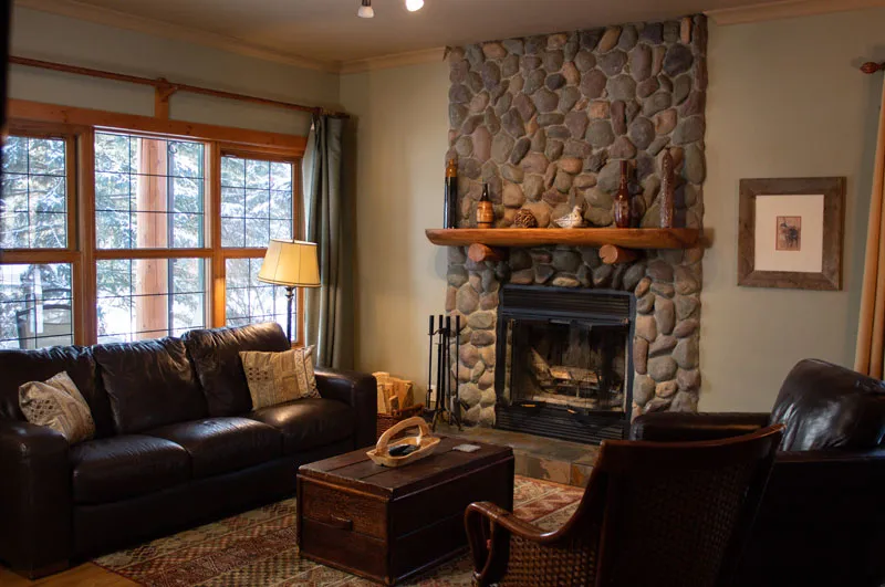 Creekside cottage interior with stone fireplace, dark leather seating, and wood-framed windows at Prairie Creek Inn.